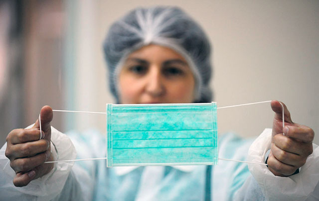 A worker shows a face mask at a hospital equipment factory in Cornella de Llobregat, near of Barcelona, Spain, Thursday, April 30, 2009. Face masks sales for the company increased from 250,000 units to 1 million per week due to the swine flu scare. (AP Photo/Manu Fernandez)